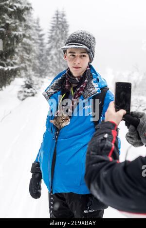 tabby cat looking from beneath boy`s jacket in fogy snowy day Stock Photo